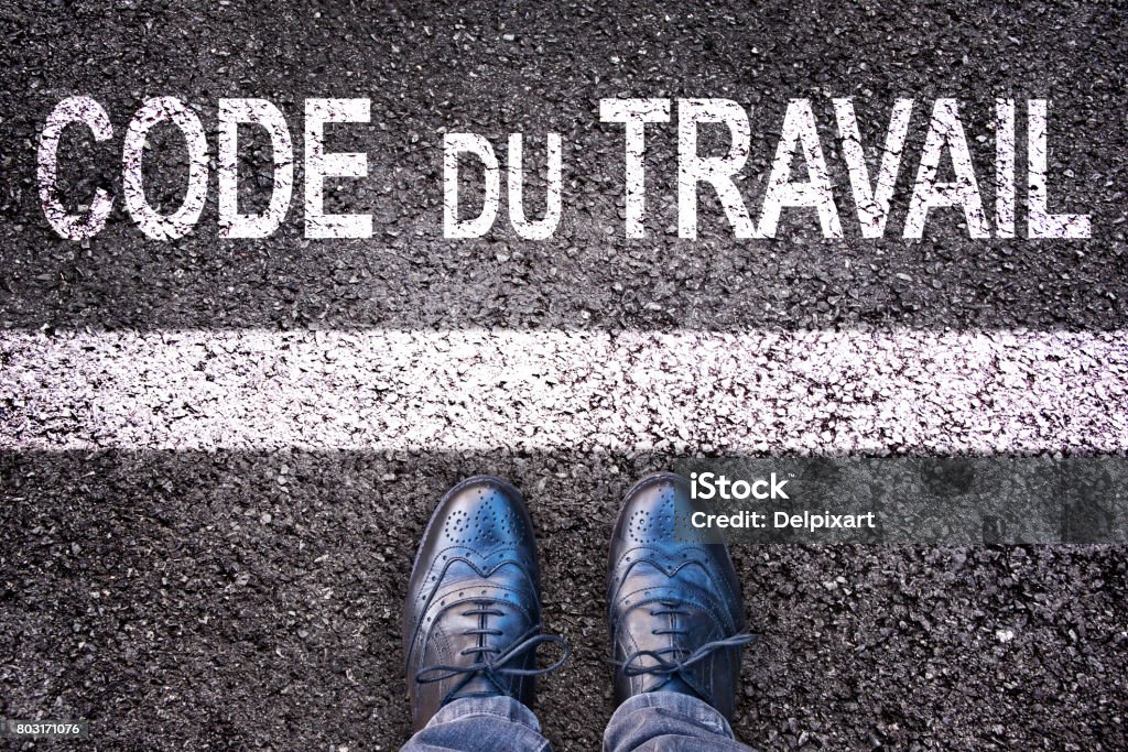 Code du travail (meaning labor code in French) written on an asphalt road background with legs Employment And Labor Stock Photo