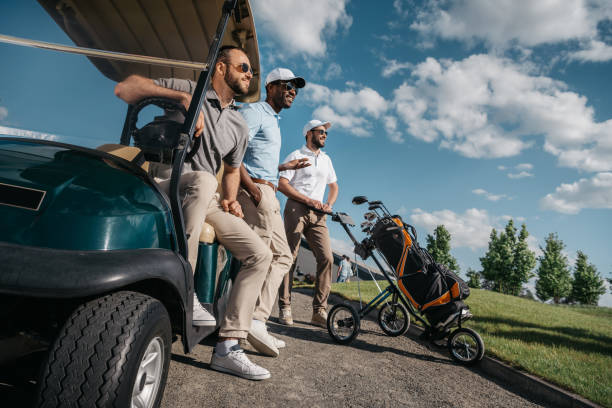 grupo de amigos sorrindo em pé perto de carrinho de golfe e desviar o olhar - friends life t20 - fotografias e filmes do acervo