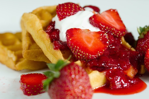 Waffles with strawberries, homemade berry sauce and cream