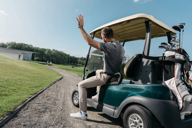 試合前にカートに乗りながら友達に手を振る人の背面図 - golf cart golf bag horizontal outdoors ストックフォトと画像