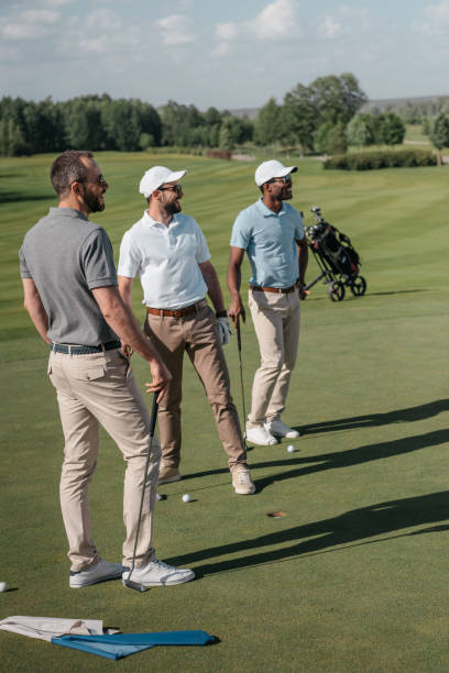 istock young multiethnic golf players looking away while standing on pitch 803212868