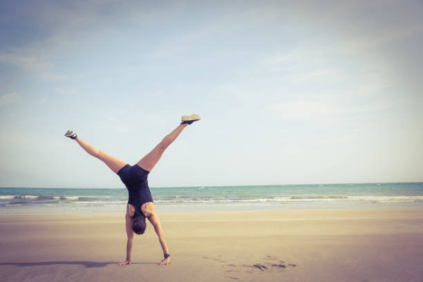 Fit woman cartwheeling on the sand at the beach