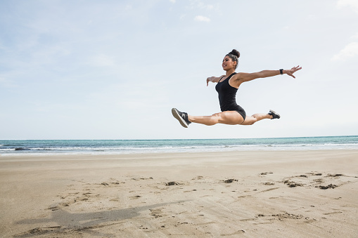 Fit woman leaping on the sand at the beach
