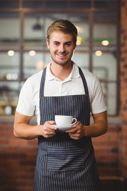 istock Handsome barista holding a cup of coffee 803213642
