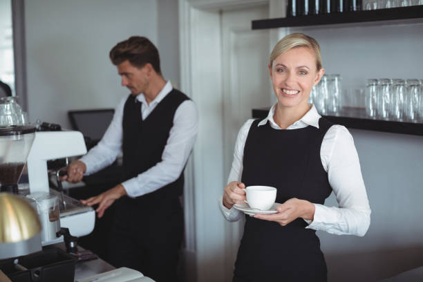 istock Smiling waitress holding cup of coffee at counter 803220194
