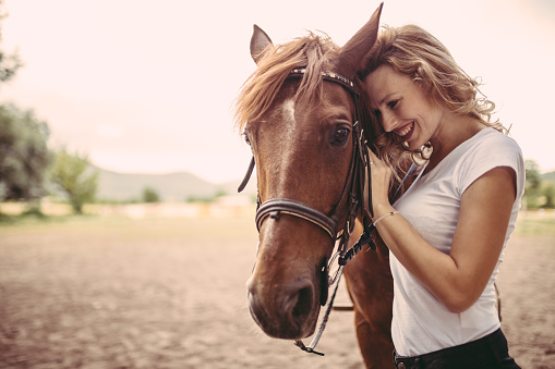 Young curly blonde woman and her horse, enjoying the summertime away from the city.