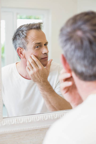 istock Handsome man looking at himself in the mirror 803256954