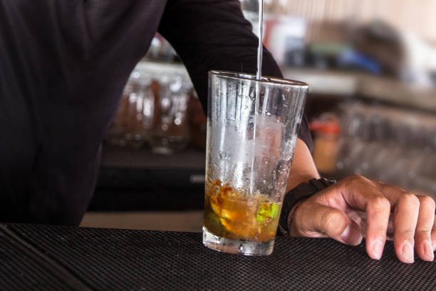 Close up male bartender pouring rum to make spiced rum mojito