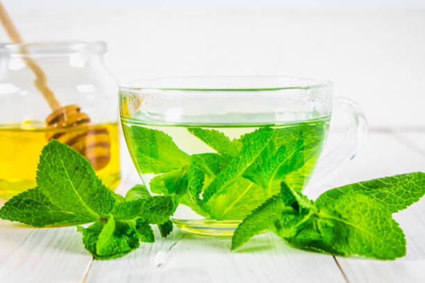 istock Mint tea in a cup, honey jar on a white wooden table. 803266218