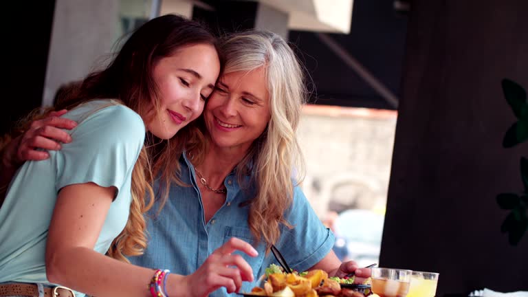 Loving mature mother and daughter sharing a meal and hugging