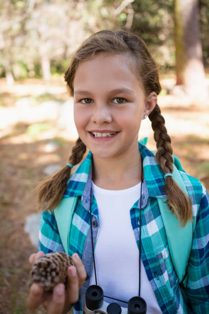 istock Smiling girl looking at pine cone in the forest 803280040