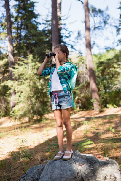 istock Girl looking through binoculars in the forest 803280066