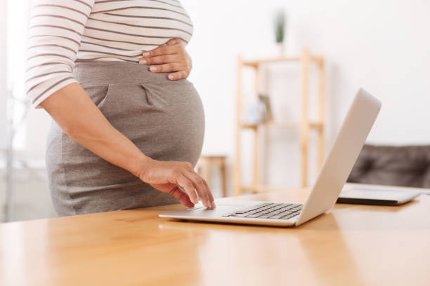 istock Nice pregnant woman using her laptop 803284854
