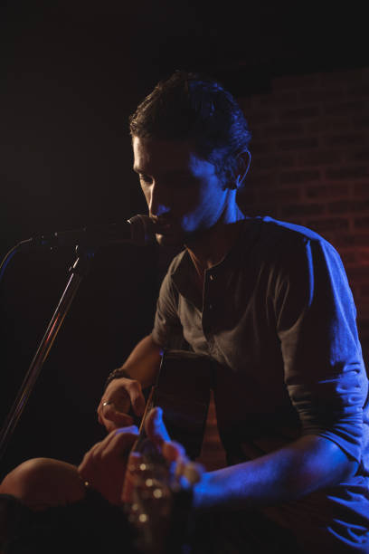 istock Male singer playing guitar while performing in nightclub 803285602
