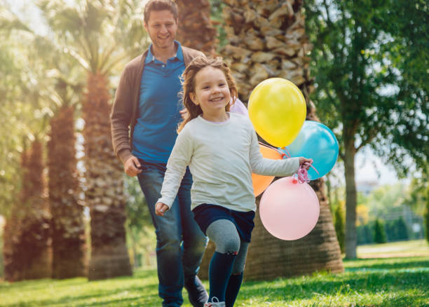 Little girl with birthday balloons. Girl is jumping with joy as a balloon pops and confetti falls around her.