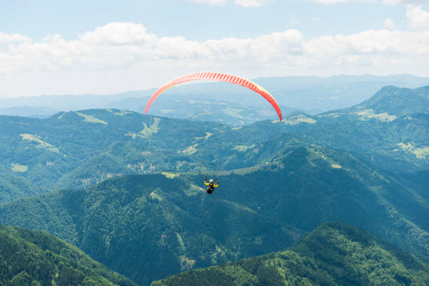 istock Paraglider flying over green hils 803311458