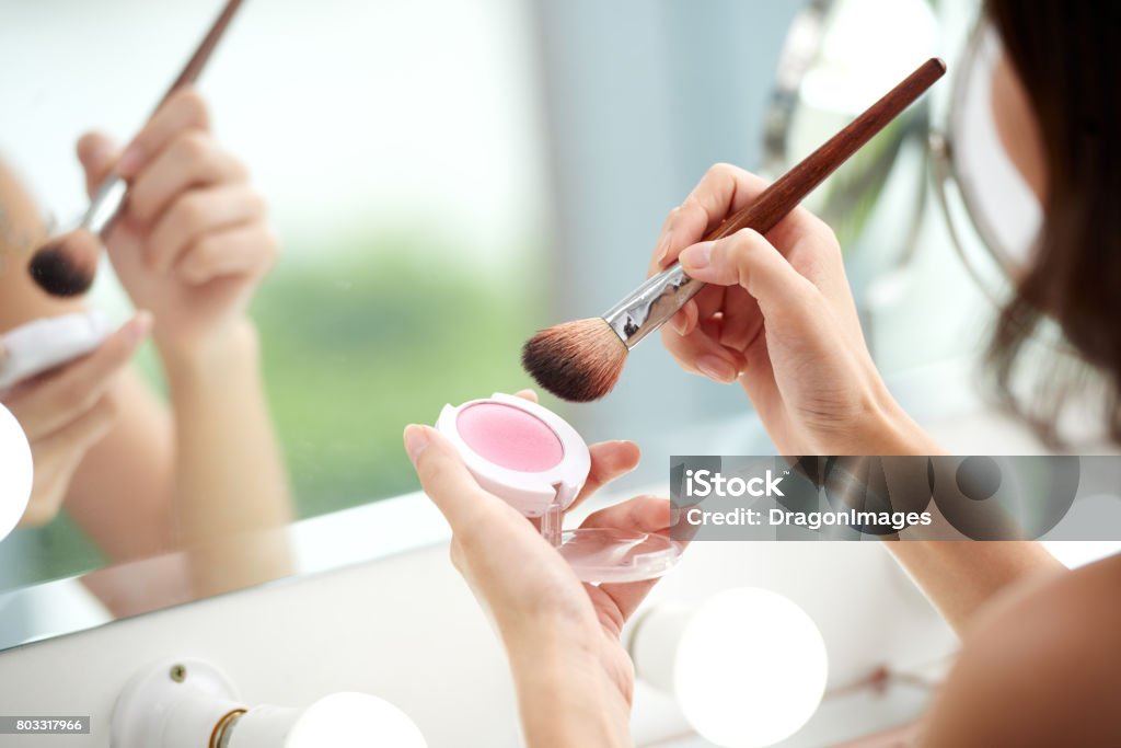 Applying blush Pink blush and brush in hands of woman Make-Up Stock Photo