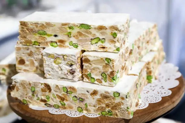 Pieces of white nougat cut and blocked, served on a wooden tray.