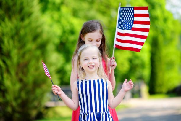 istock Two adorable little sisters holding american flags outdoors on beautiful summer day 803326448