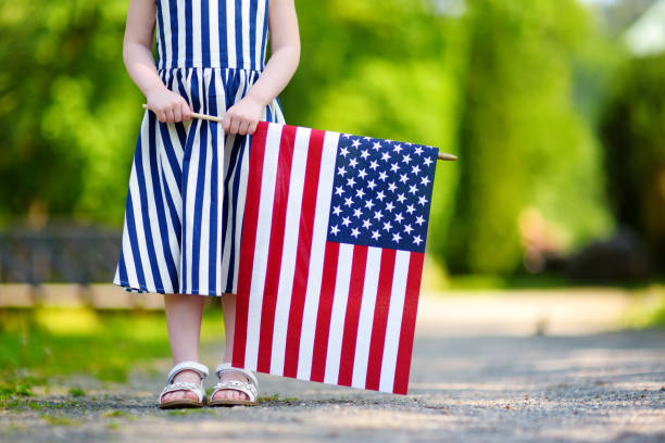 adorable petite fille tenant le drapeau américain à l’extérieur jour bel été - fourth of july honor freedom square photos et images de collection