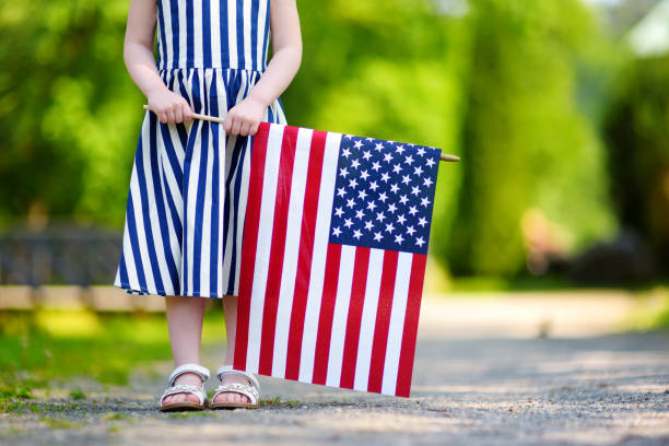 adorable little girl holding american flag outdoors on beautiful summer day - child flag fourth of july little girls imagens e fotografias de stock