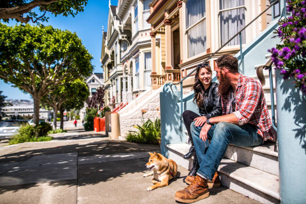 街歩きの犬とのカップル - タウンハウス ストックフォトと画像