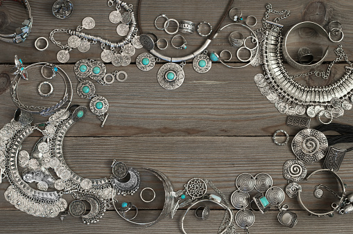 Bohemian style silver jewelry set on grey old wooden background. Top view point.