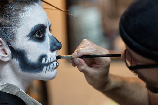 Makeup artist applying skeleton makeup on a young woman.