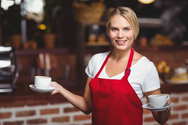 istock Pretty waitress holding two cups of coffees 803372342
