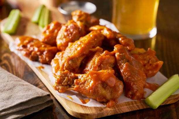 istock sauced buffalo chicken wings on wooden board with celery 803382570