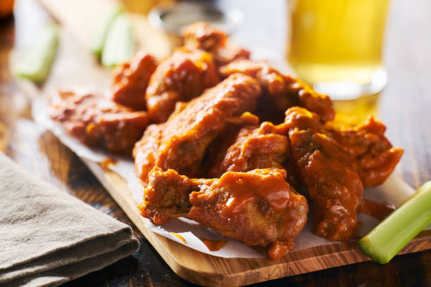 istock sauced buffalo chicken wings on wooden board with celery 803382848