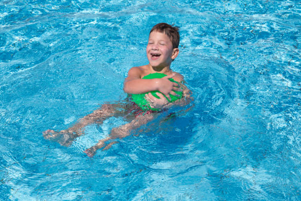 istock Little boy playing with ball in the pool 803407488