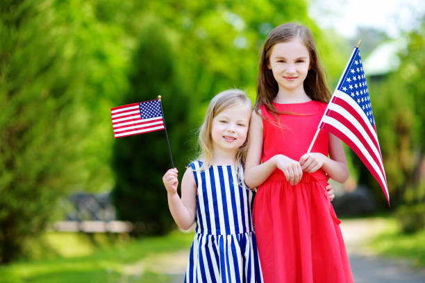 istock Two adorable little sisters holding american flags outdoors on beautiful summer day 803409204