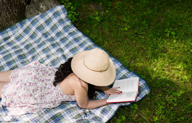 istock Woman reading a book outside in the grass 803411846