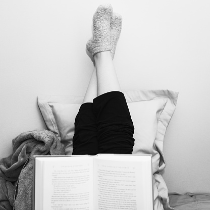 Relaxed woman in the morning.  Woman reading a book in bed.  Black & white photograph.