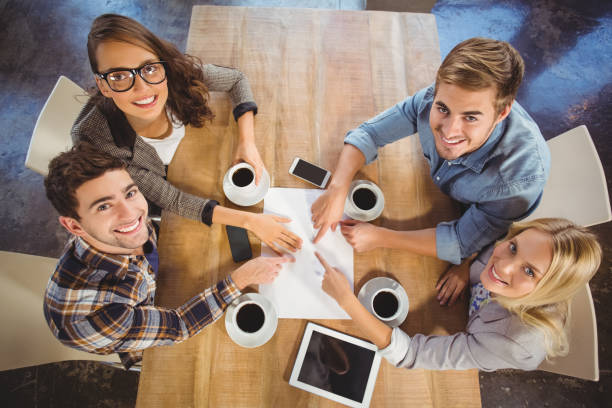 istock Smiling friends drinking coffee and pointing on paper 803420544