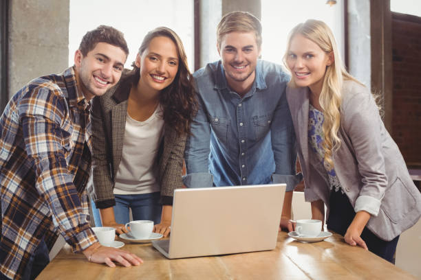 istock Smiling friends standing around laptop 803420734