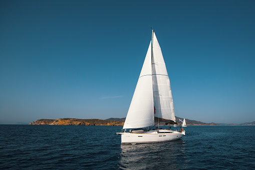 Group of attractive young women spending time on sailing vacation. They are enjoying, having fun, sunbathing, taking photos, jumping into the sea from the sailboat They look happy and relaxed.