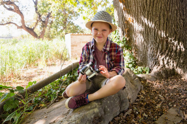istock Smiling boy sitting on the rock with binoculars 803435086