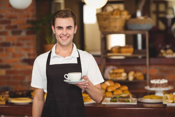 istock Smiling barista holding cup of coffee 803456674
