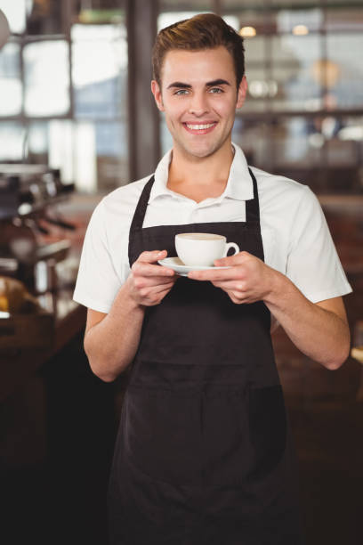 istock Smiling barista holding cup of coffee 803456740