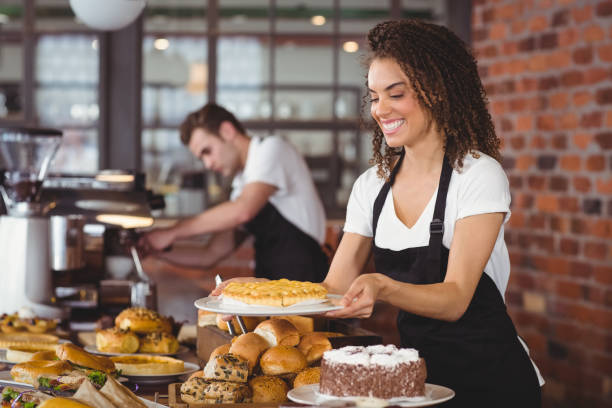 istock Smiling waitress holding cake in front of colleague 803474056