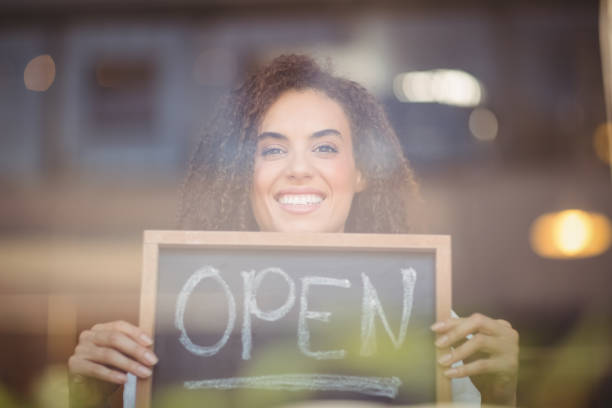istock Smiling waitress showing chalkboard with open sign 803500260