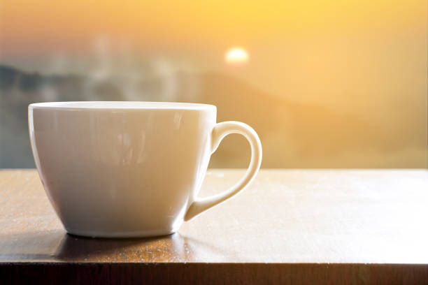 istock Cup of coffee on wooden table in sunrise 803500550