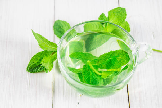 istock Mint tea in a cup on a white wooden table. Top view 803503380