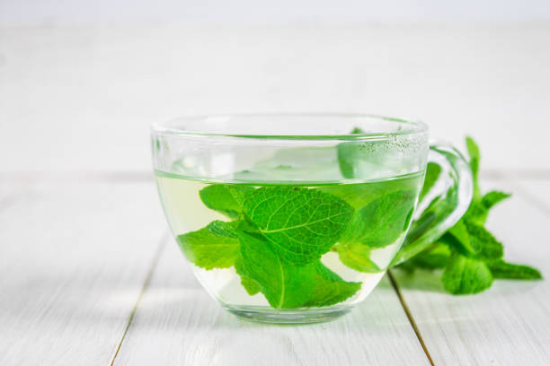 istock Mint tea in a cup on a white wooden table. 803503452