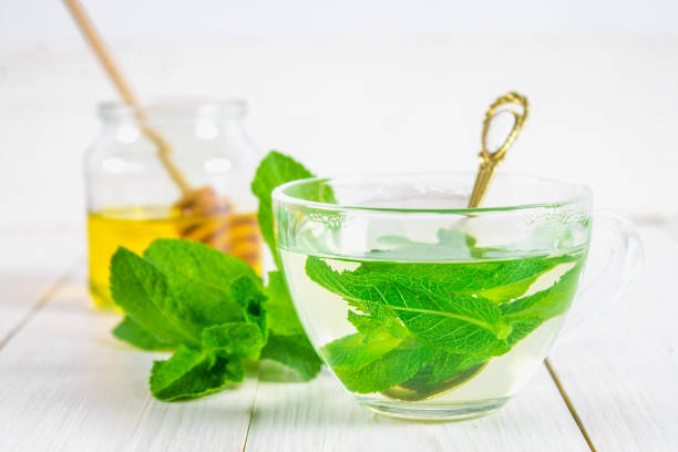 istock Mint tea in a cup, honey jar on a white wooden table. 803506808