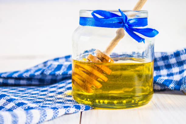 istock A honey jar with a spoon, on a white table with a blue towel. 803506812