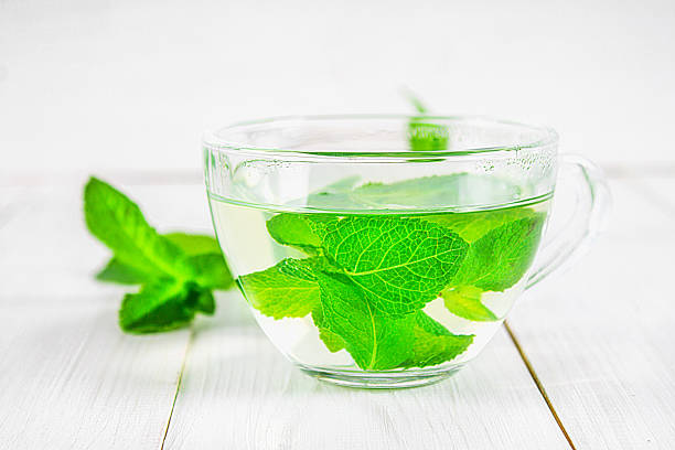 istock Mint tea in a cup on a white wooden table. 803506818