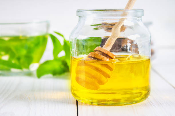 istock A honey jar with a spoon on a white table. In the background, mint. 803506820